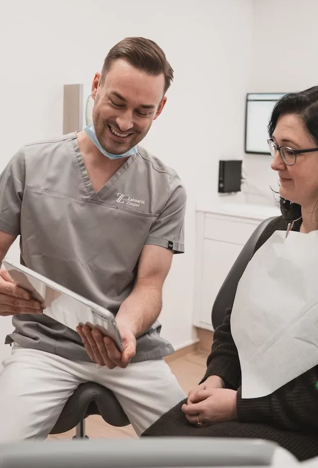 Zahnarzt Ziegler klärt eine Patientin am iPad auf